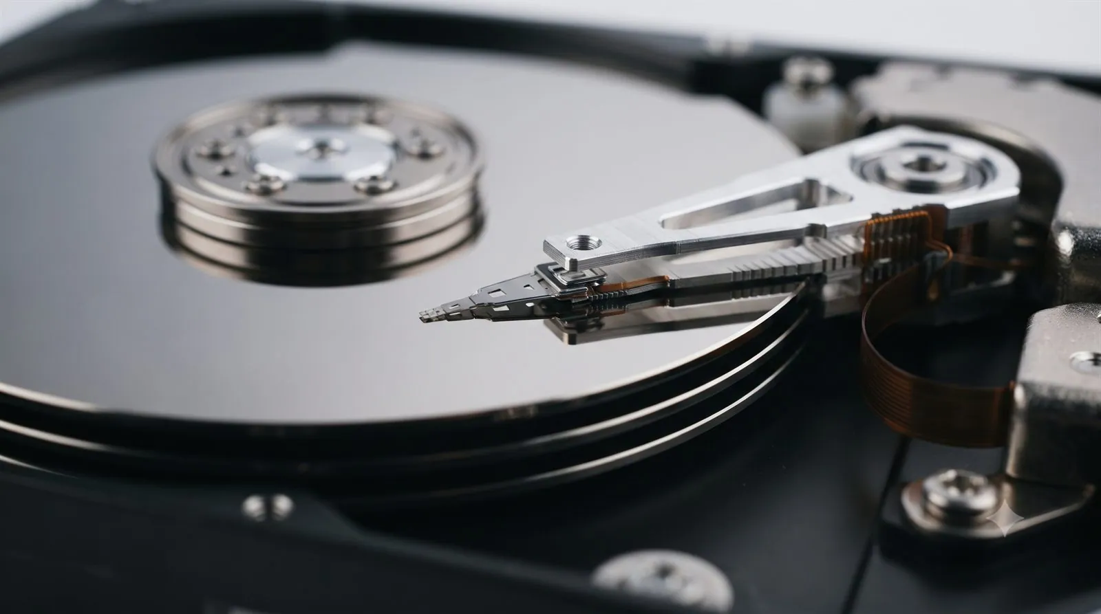 A close-up of an open hard drive showing the read/write head and actuator arm